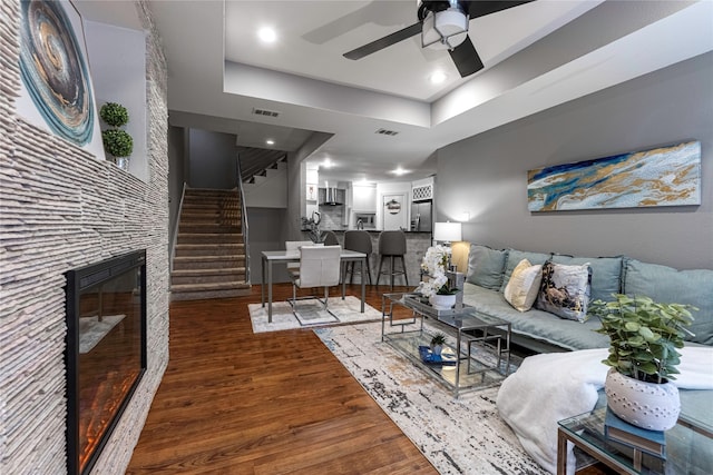 living room with ceiling fan, a tray ceiling, and dark hardwood / wood-style flooring