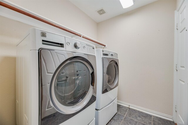 clothes washing area with washing machine and dryer and dark tile patterned floors