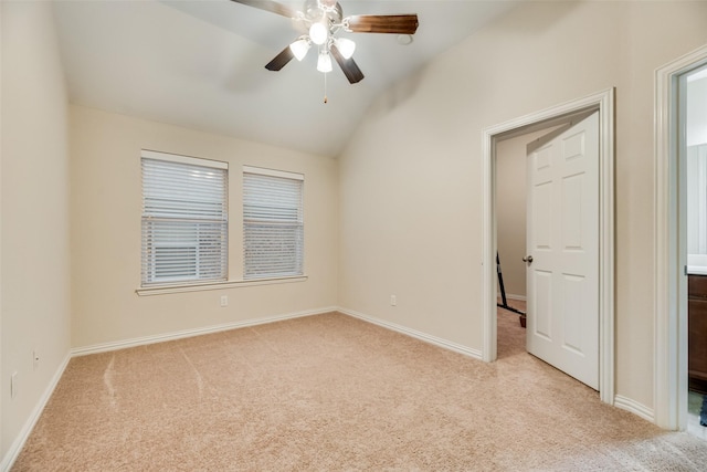 empty room with ceiling fan, vaulted ceiling, and light carpet