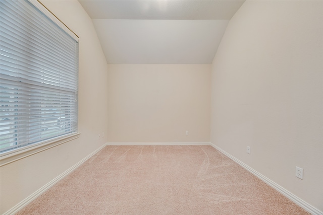 carpeted spare room featuring vaulted ceiling