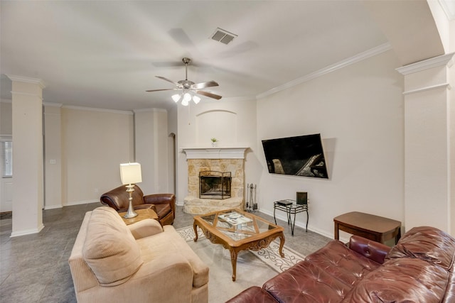 living room featuring ornate columns, ornamental molding, a stone fireplace, and ceiling fan