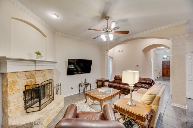 living room featuring ceiling fan, light tile patterned floors, a stone fireplace, and crown molding