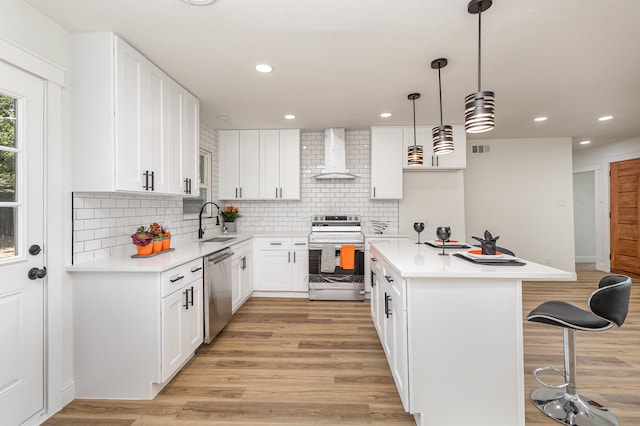 kitchen with white range oven, wall chimney range hood, hanging light fixtures, light wood-type flooring, and sink