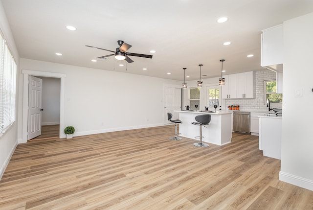 kitchen with light wood-type flooring, a kitchen breakfast bar, dishwasher, a center island, and ceiling fan