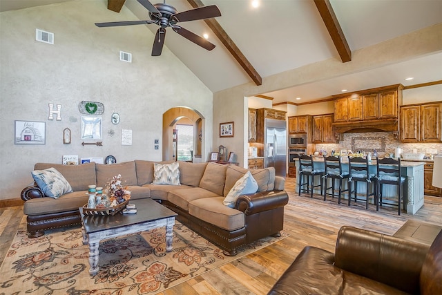 living room with beam ceiling, high vaulted ceiling, light hardwood / wood-style flooring, and ceiling fan