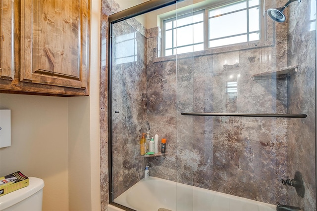 bathroom featuring enclosed tub / shower combo, toilet, and plenty of natural light