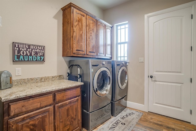 clothes washing area with cabinets, washing machine and dryer, and wood-type flooring