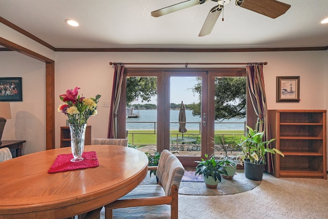 dining space featuring carpet flooring, ornamental molding, and a water view