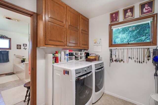 laundry area with separate washer and dryer and cabinets