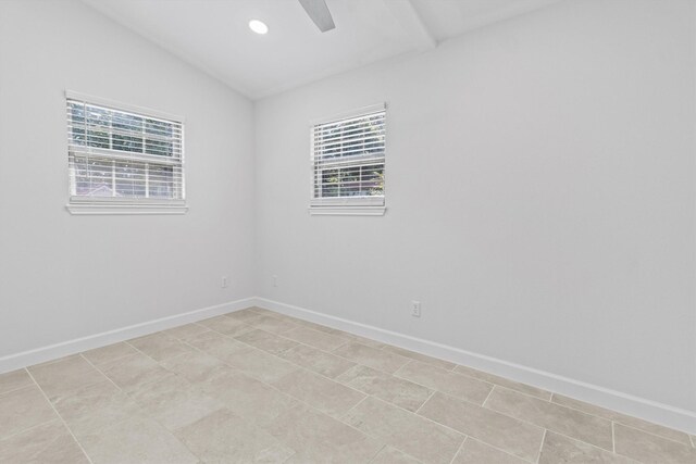 tiled spare room featuring plenty of natural light and lofted ceiling