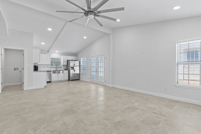 unfurnished living room featuring light tile patterned floors, high vaulted ceiling, ceiling fan, sink, and french doors