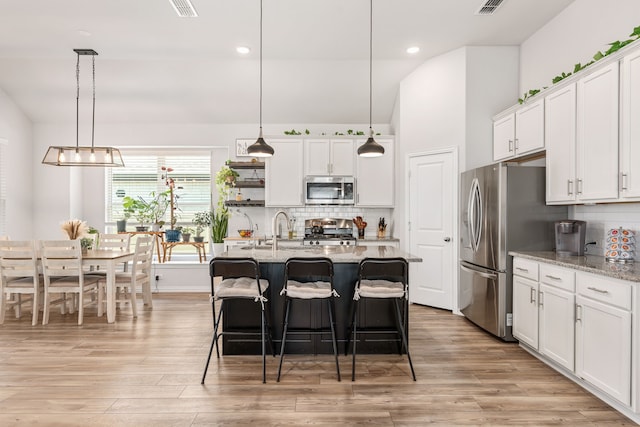 kitchen featuring pendant lighting, light hardwood / wood-style flooring, stainless steel appliances, and white cabinetry