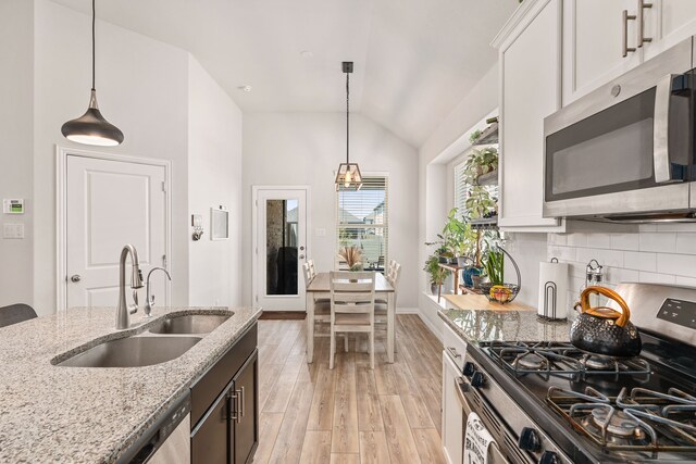 kitchen featuring decorative light fixtures, white cabinets, stainless steel appliances, and sink