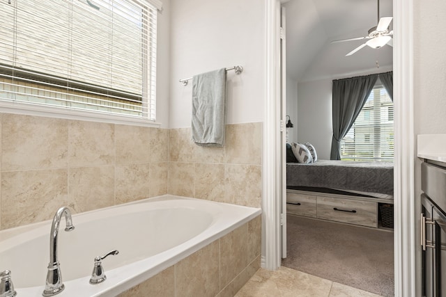 bathroom featuring tile patterned flooring, vanity, a relaxing tiled tub, ceiling fan, and lofted ceiling