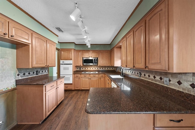 kitchen with white appliances, visible vents, dark stone counters, a sink, and dark wood-type flooring