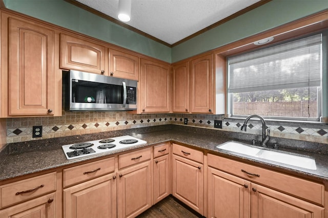 kitchen with dark stone countertops, crown molding, sink, and white stovetop