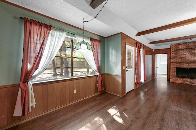 unfurnished dining area featuring a textured ceiling, wood finished floors, and wainscoting