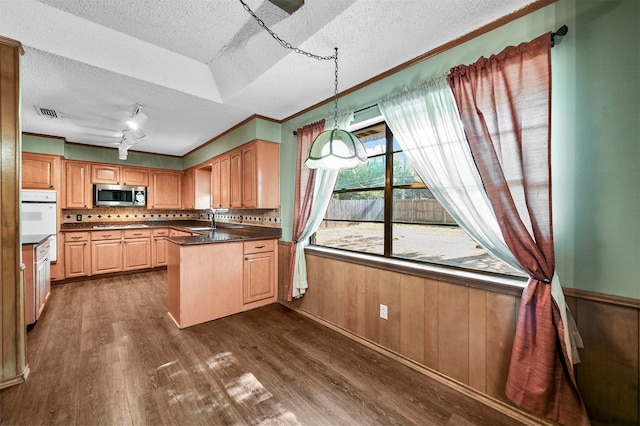 kitchen with a textured ceiling, wooden walls, hanging light fixtures, and dark wood-type flooring