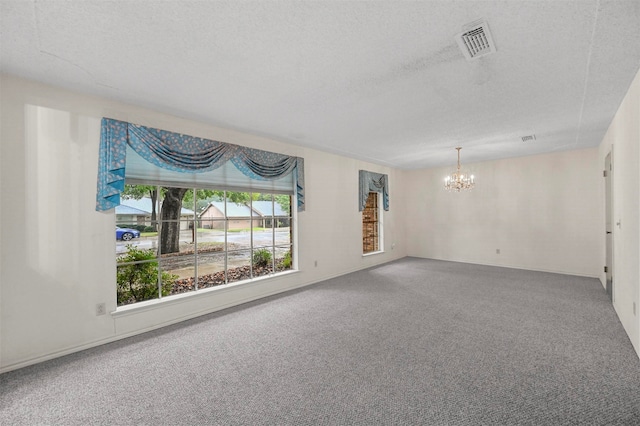 unfurnished room with carpet flooring, a textured ceiling, and a chandelier