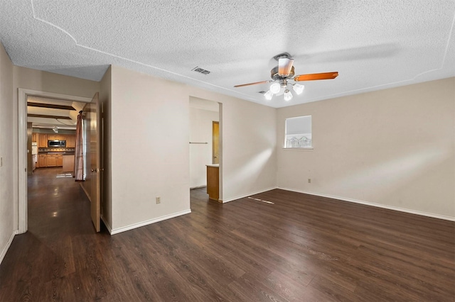 empty room featuring a ceiling fan, baseboards, dark wood-style floors, visible vents, and a textured ceiling