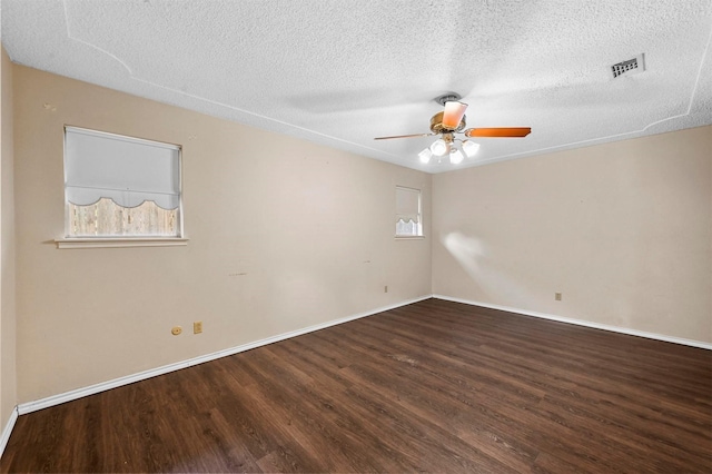 unfurnished room with visible vents, a textured ceiling, wood finished floors, baseboards, and ceiling fan