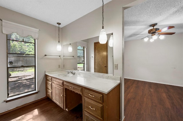 kitchen with a sink, dark wood-type flooring, brown cabinetry, and a textured ceiling