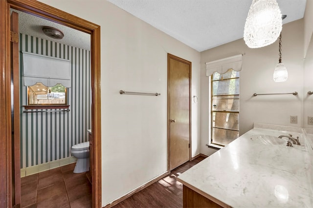 bathroom with hardwood / wood-style floors, vanity, toilet, and a textured ceiling