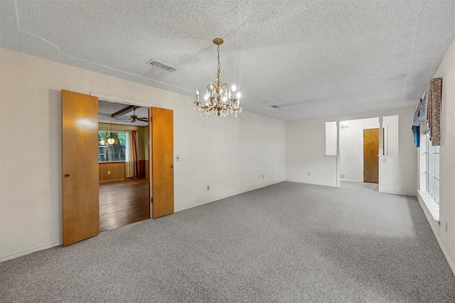 empty room featuring carpet, a textured ceiling, and a notable chandelier