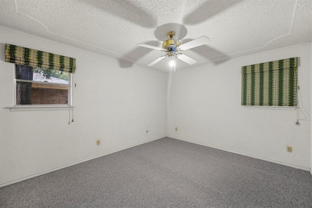 spare room featuring a textured ceiling, carpet, baseboards, and ceiling fan