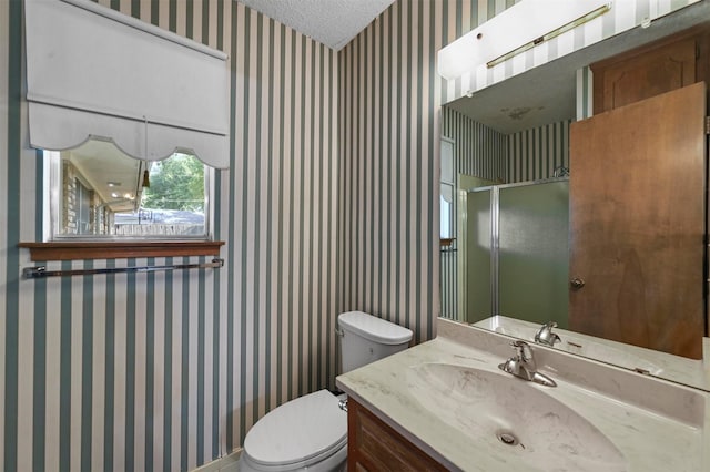 bathroom with wallpapered walls, toilet, a stall shower, a textured ceiling, and vanity