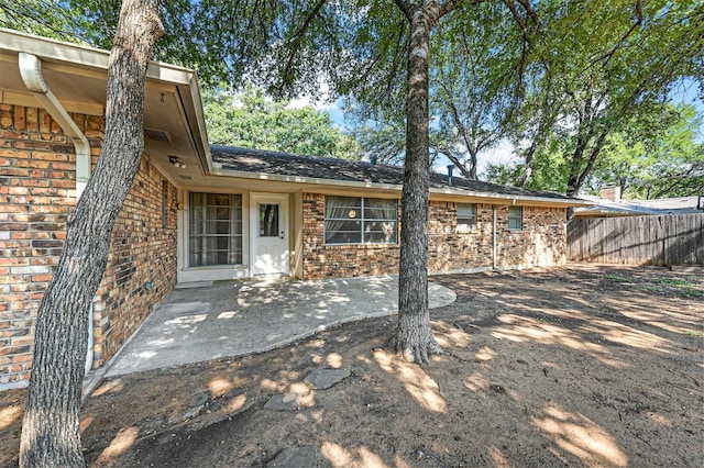 rear view of property featuring brick siding, a patio, and fence