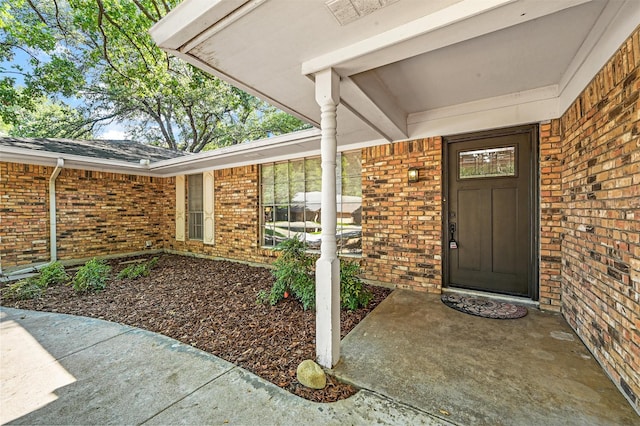 view of exterior entry featuring brick siding