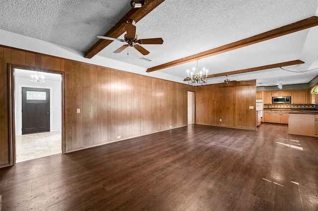 unfurnished living room with visible vents, beam ceiling, dark wood-type flooring, a textured ceiling, and wood walls