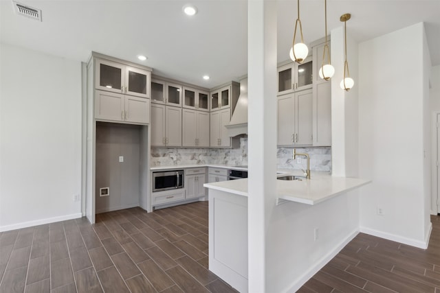 kitchen featuring decorative backsplash, custom exhaust hood, appliances with stainless steel finishes, dark wood-type flooring, and sink