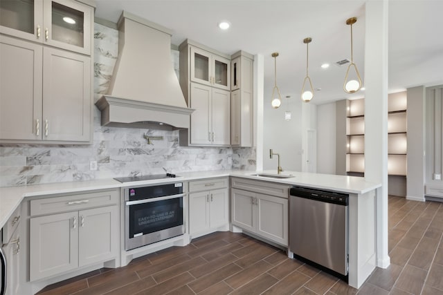 kitchen with appliances with stainless steel finishes, sink, custom range hood, and decorative backsplash