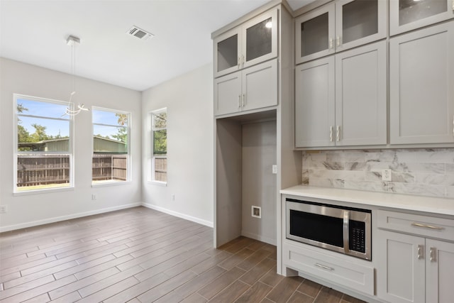 kitchen with tasteful backsplash, gray cabinets, dark wood-type flooring, and hanging light fixtures