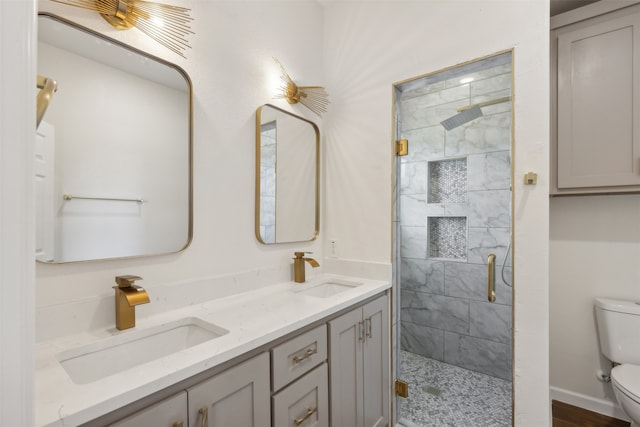 bathroom with a shower with door, double vanity, and toilet