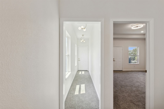 hall featuring an inviting chandelier and carpet floors