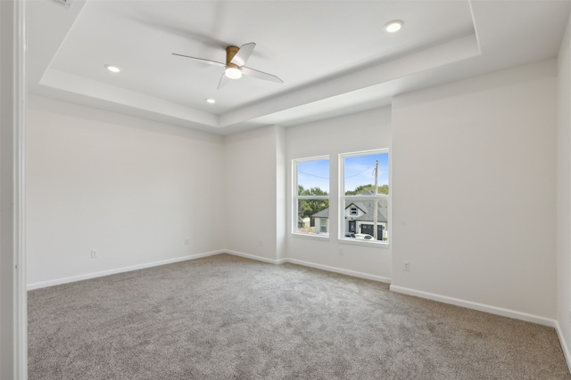 carpeted empty room with ceiling fan and a tray ceiling