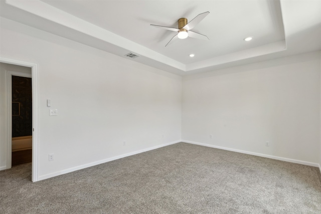 carpeted empty room with a tray ceiling and ceiling fan