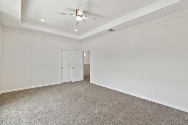 carpeted spare room featuring ceiling fan and a tray ceiling