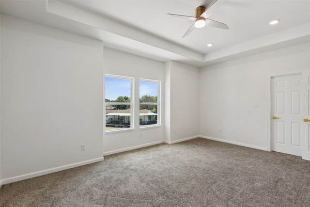 spare room with ceiling fan, a raised ceiling, and carpet flooring