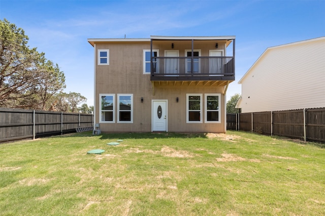 rear view of property featuring a balcony and a yard