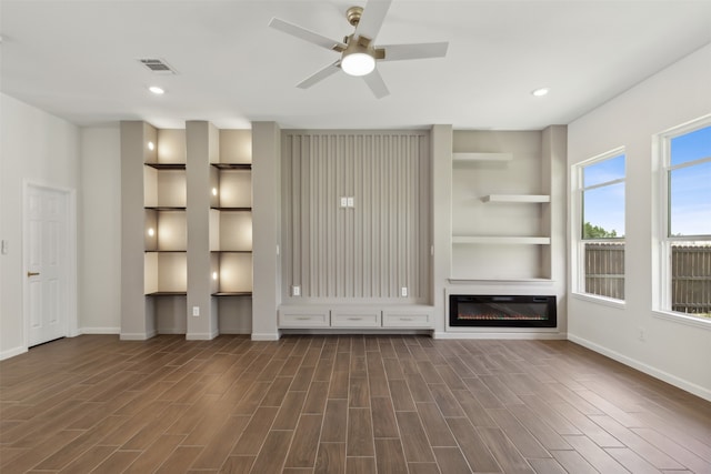 unfurnished living room featuring ceiling fan, dark hardwood / wood-style floors, and built in shelves