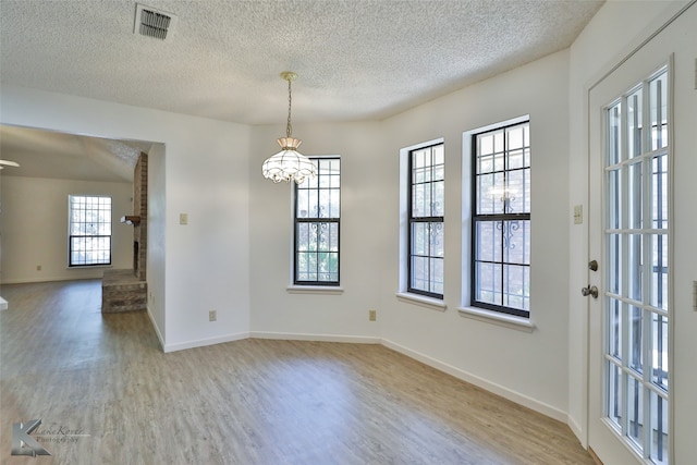 interior space featuring hardwood / wood-style flooring, a textured ceiling, and a chandelier