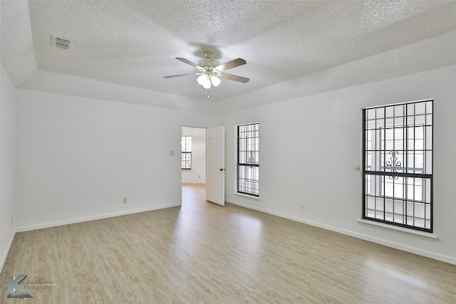 spare room with a textured ceiling, plenty of natural light, ceiling fan, and light hardwood / wood-style floors