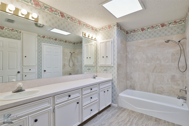 bathroom with hardwood / wood-style flooring, tiled shower / bath combo, a textured ceiling, and dual vanity