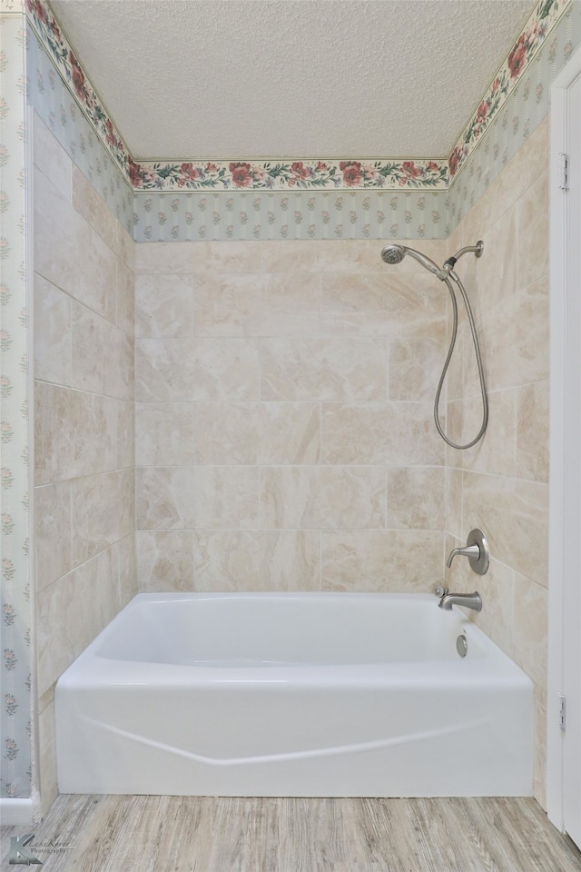 bathroom featuring a textured ceiling and tiled shower / bath