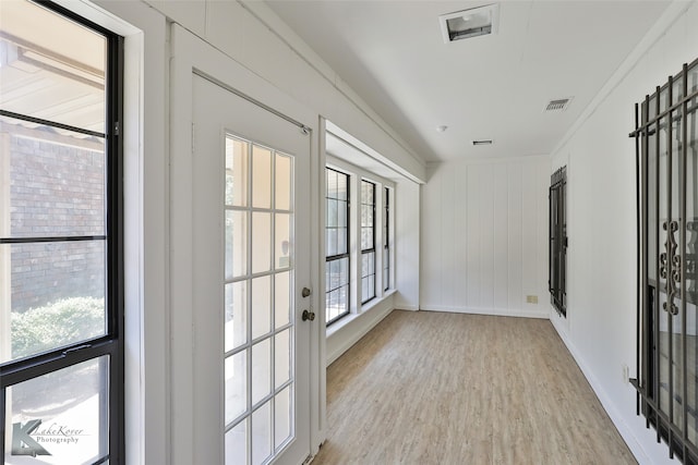 doorway to outside featuring ornamental molding, a wealth of natural light, and light hardwood / wood-style floors