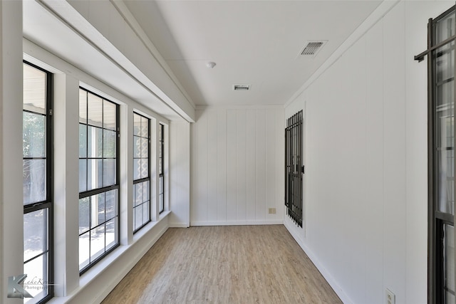 empty room featuring light wood-type flooring and crown molding